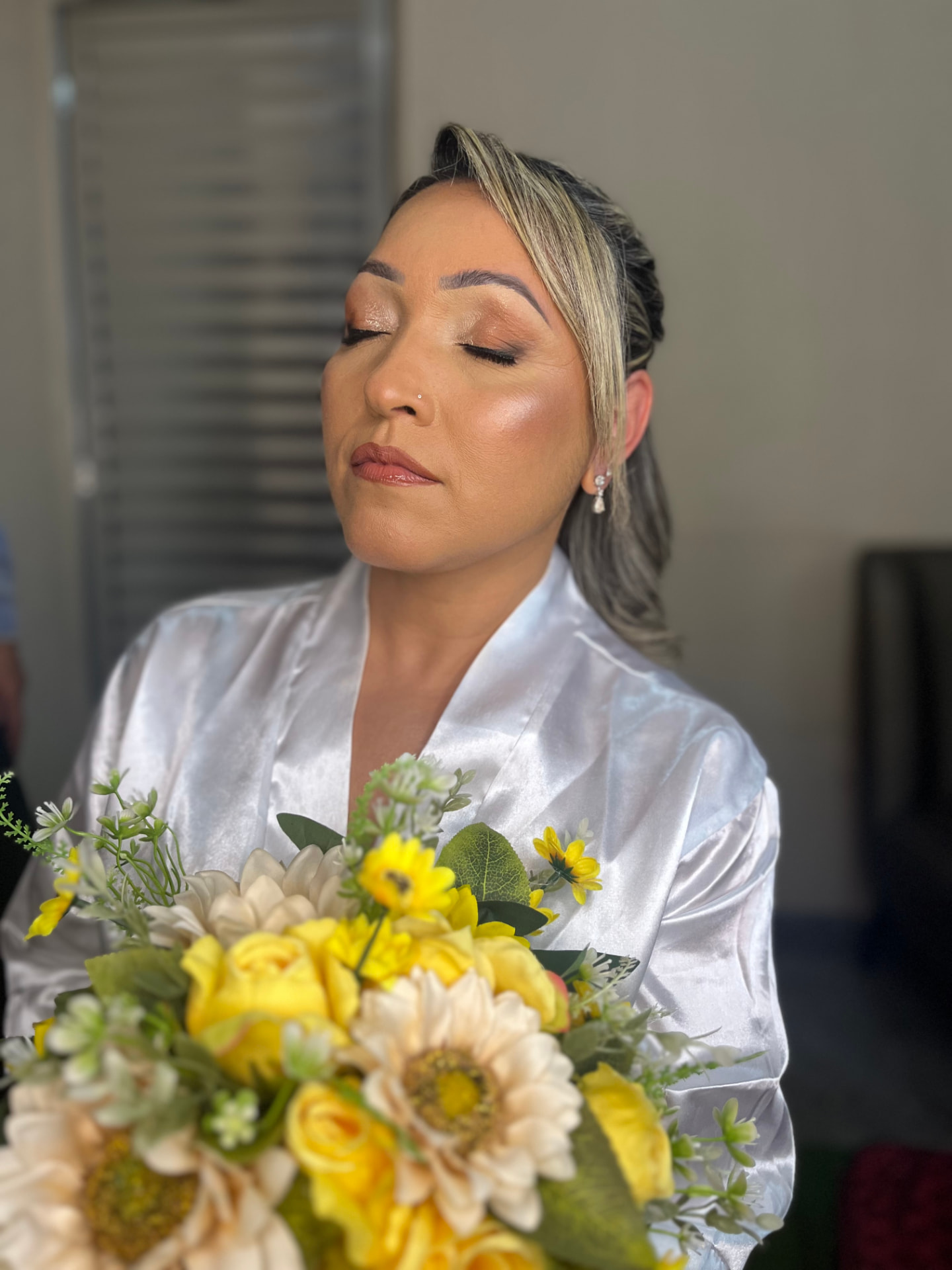 Noiva de olhos fechados com pele iluminada e buquê de flores