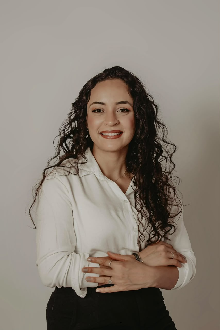 Vitória Mariano, maquiadora profissional, de braços cruzados e sorriso